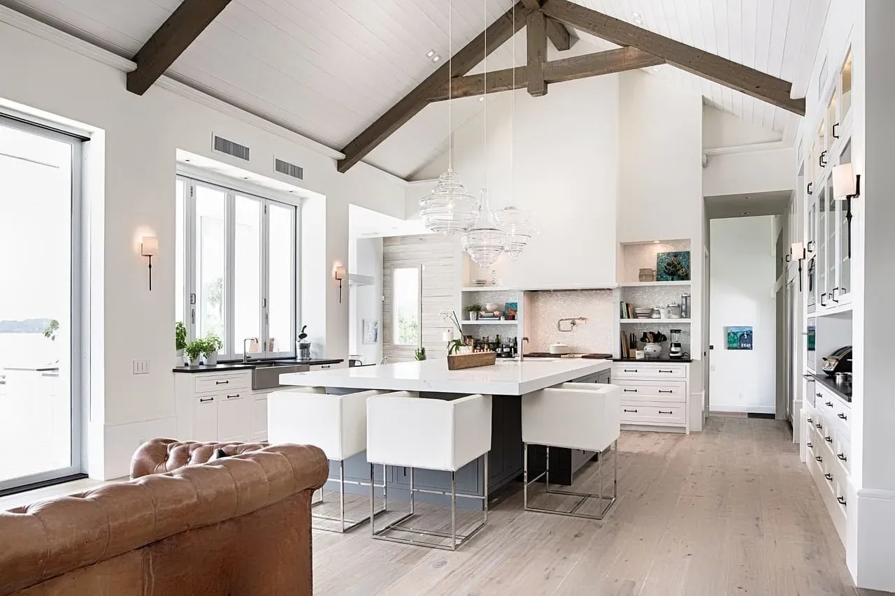 Bright white kitchen with a vaulted beamed ceiling and pendant lights over a long island