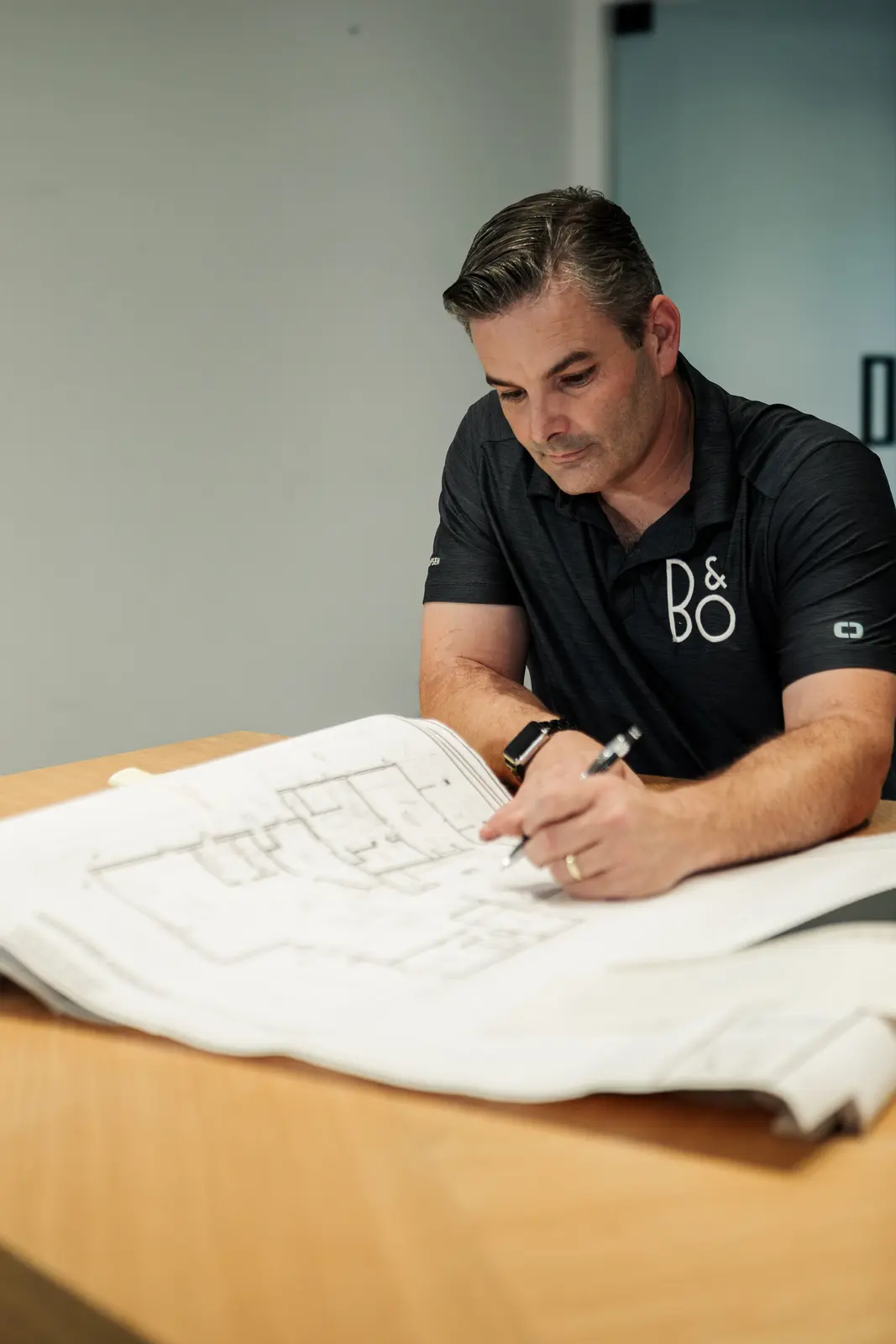 Bryan Watt marking up a set of architectural drawings, pen on the plan
