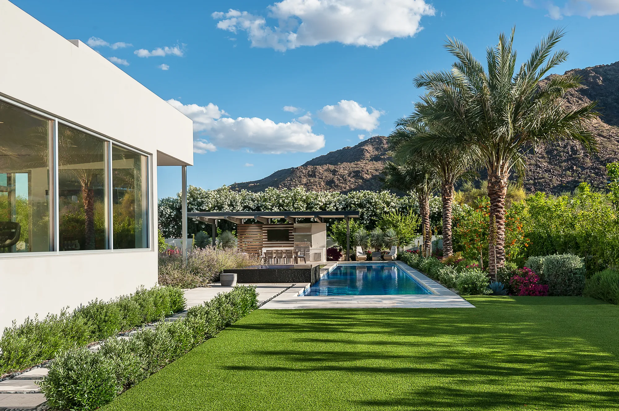 Rear elevation of a Paradise Valley project home, looking across the pool and lawn toward the covered outdoor living area