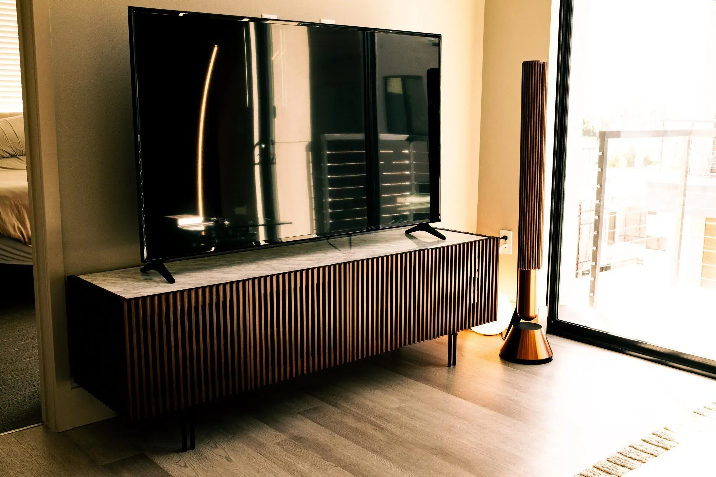 Bang & Olufsen Beolab 28 speaker beside a slatted-wood media credenza and television in a client living room