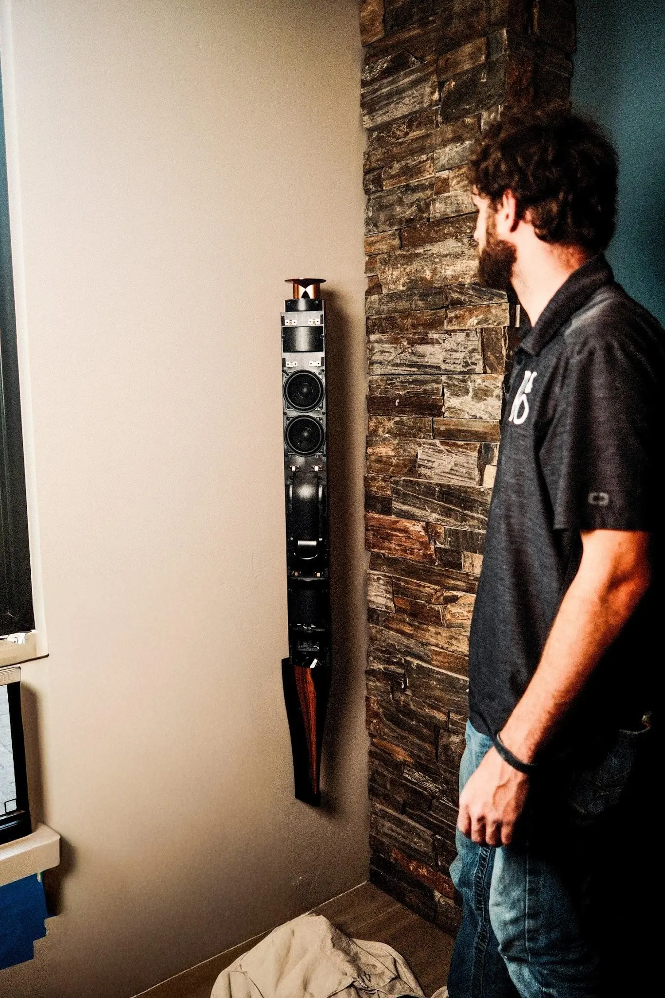 A Watt Integration technician aligns the Beolab 18 on the stacked-stone wall during installation